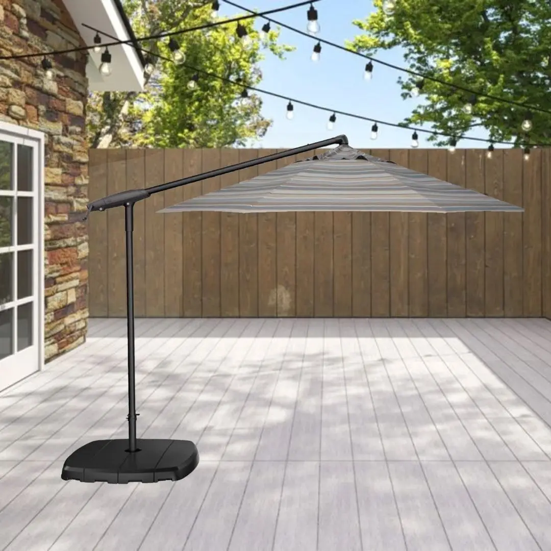 Cantilever patio umbrella on a weighted base over a wooden deck, with string lights and a wooden privacy fence in the background.