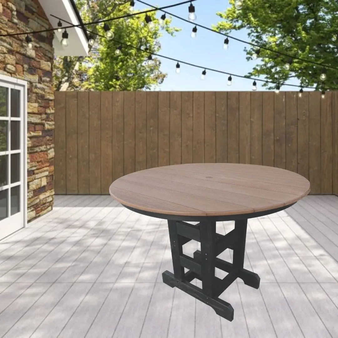 Round wooden outdoor table on a black trestle base in a sunny backyard deck, with string lights and a wooden fence in the background.